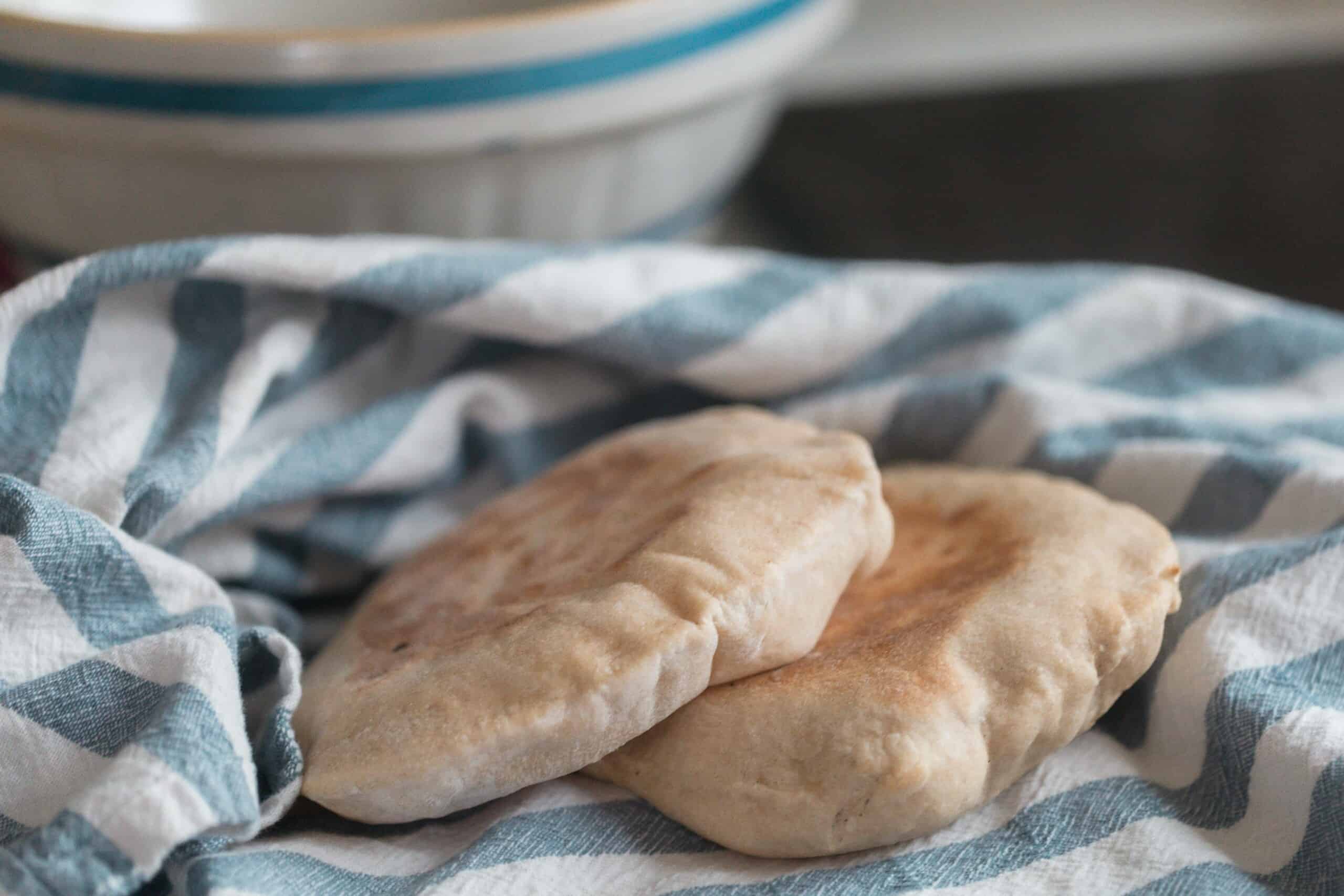 two sourdough pita bread on a white and blue stripped towel