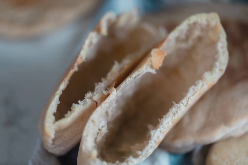 a pita bread sliced in half revealing a large air pocket