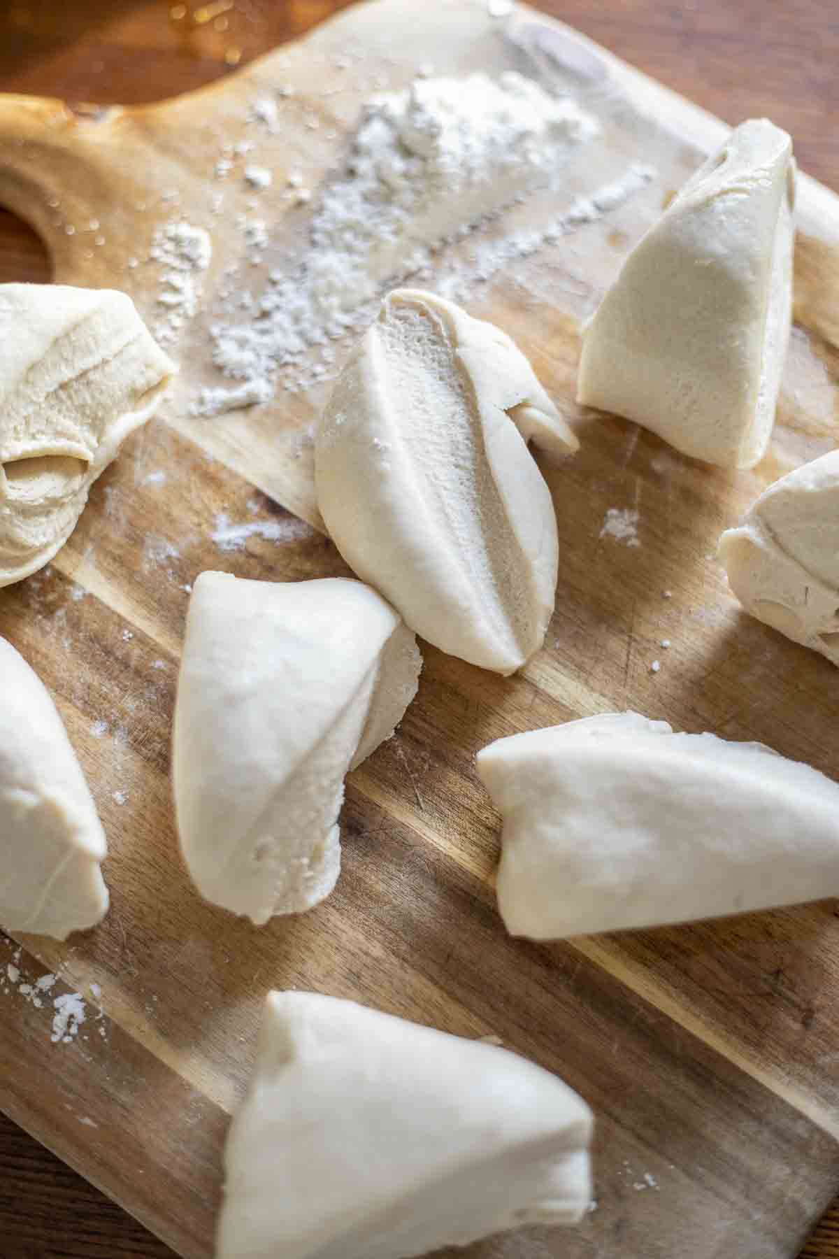 sourdough pretzel dough cut into pieces on a wood cutting board