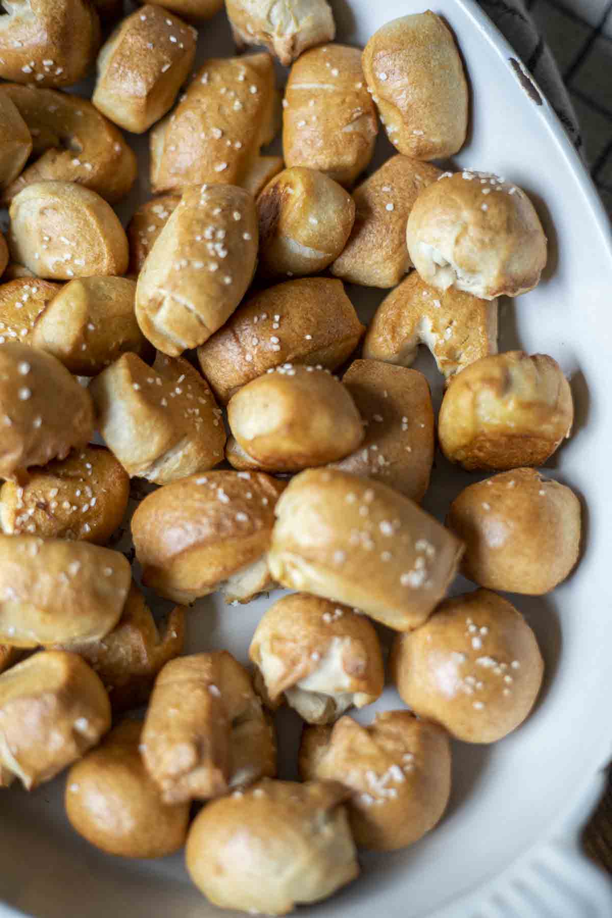 overhead photo of sourdough pretzel bites topped with course salt in a white enameled dish