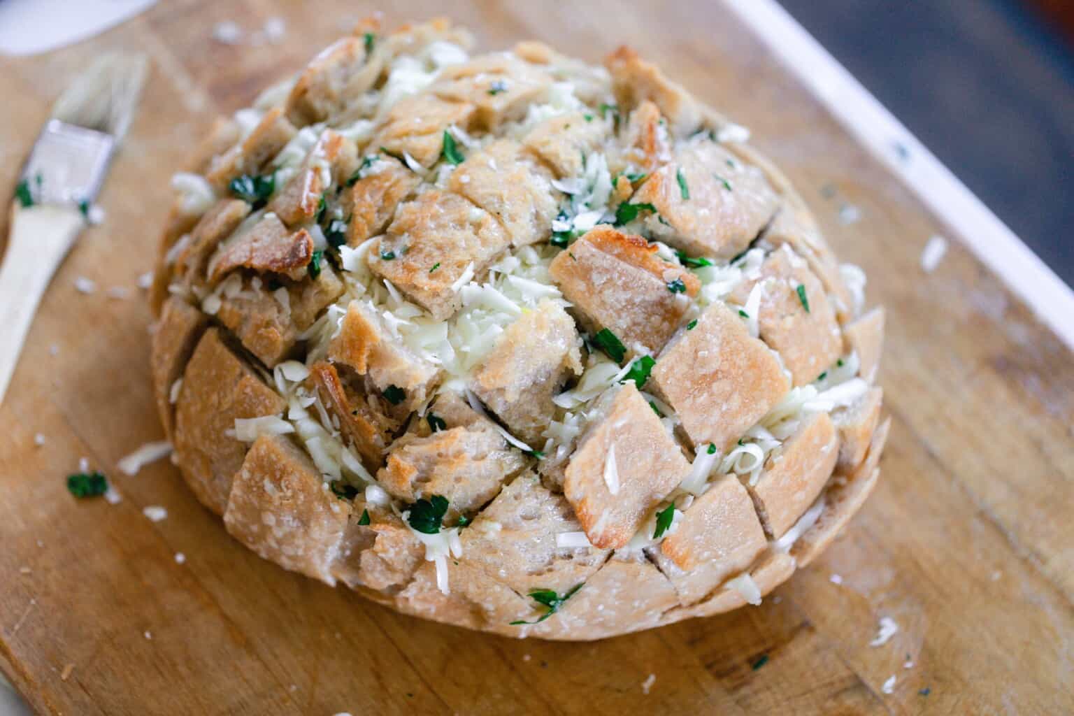 sourdough pull apart bread ready to go in the oven on a wooden counter top with knife on side