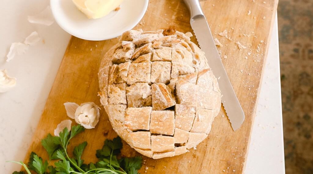 sourdough boule cut with knife to the side and garlic, parsley and butter