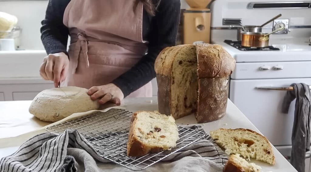 woman wearing a pink apron scoring a loaf of bread