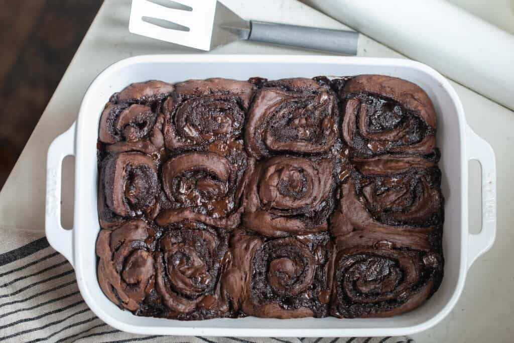 overhead photo of double chocolate sourdough rolls in a white baking dish on a white countertop