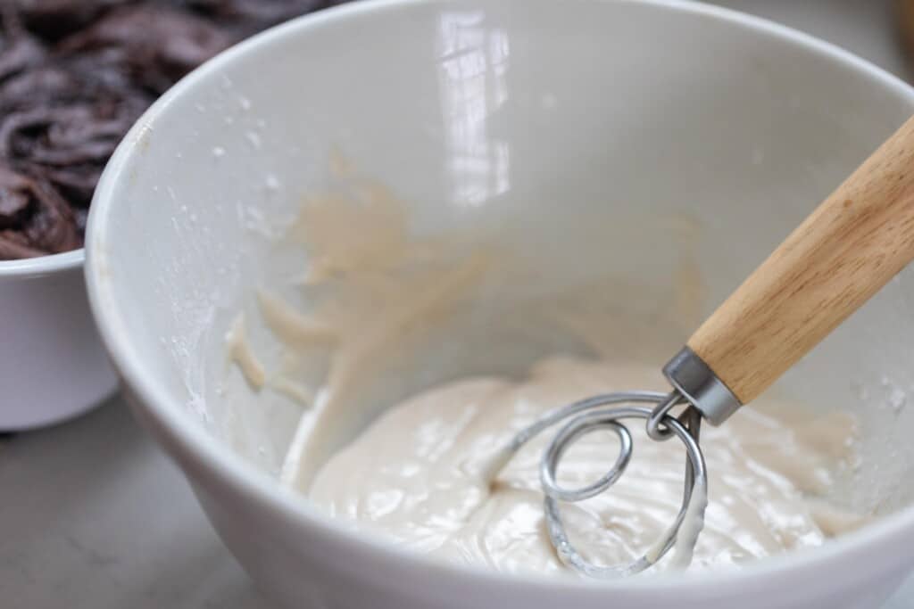 vanilla glaze in a bowl with a dough whisk