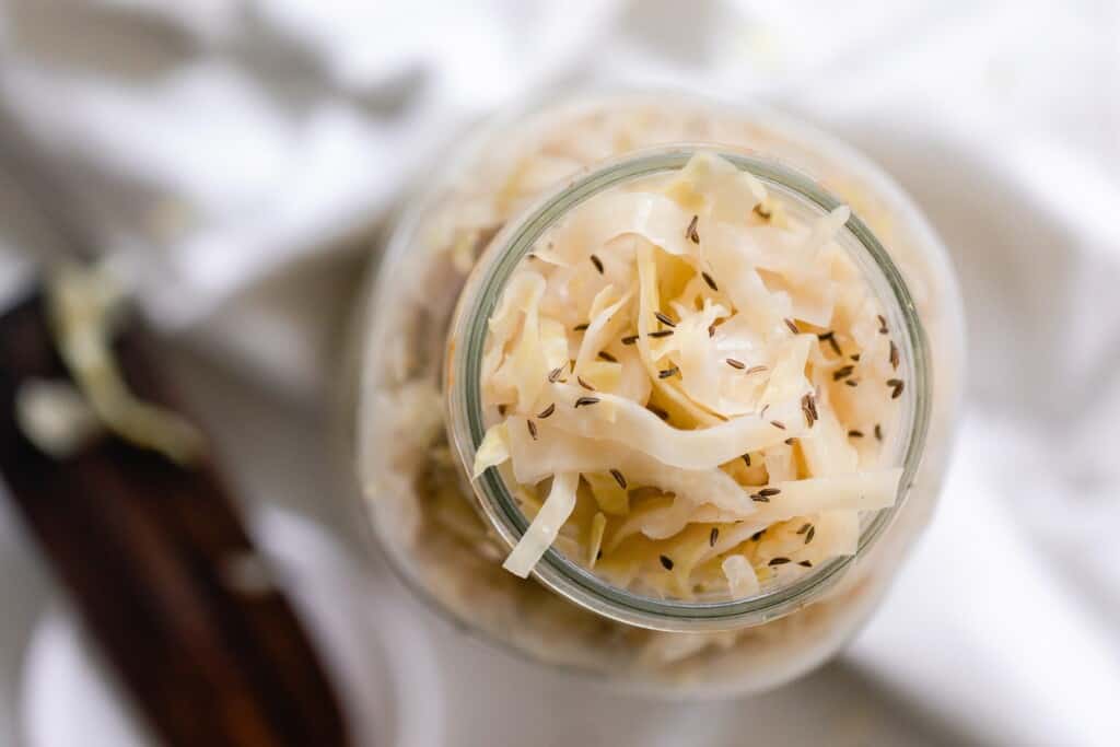 seeds added to the top of a jar of sauerkraut