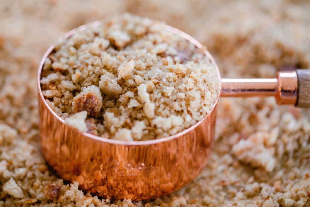 a copped and wood dry measuring up with sourdough breadcrumbs. The measuring cup rests on more bread crumbs