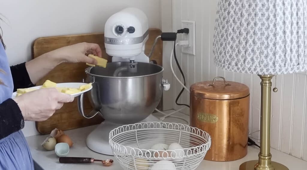 adding butter to a stand mixer mixing dough