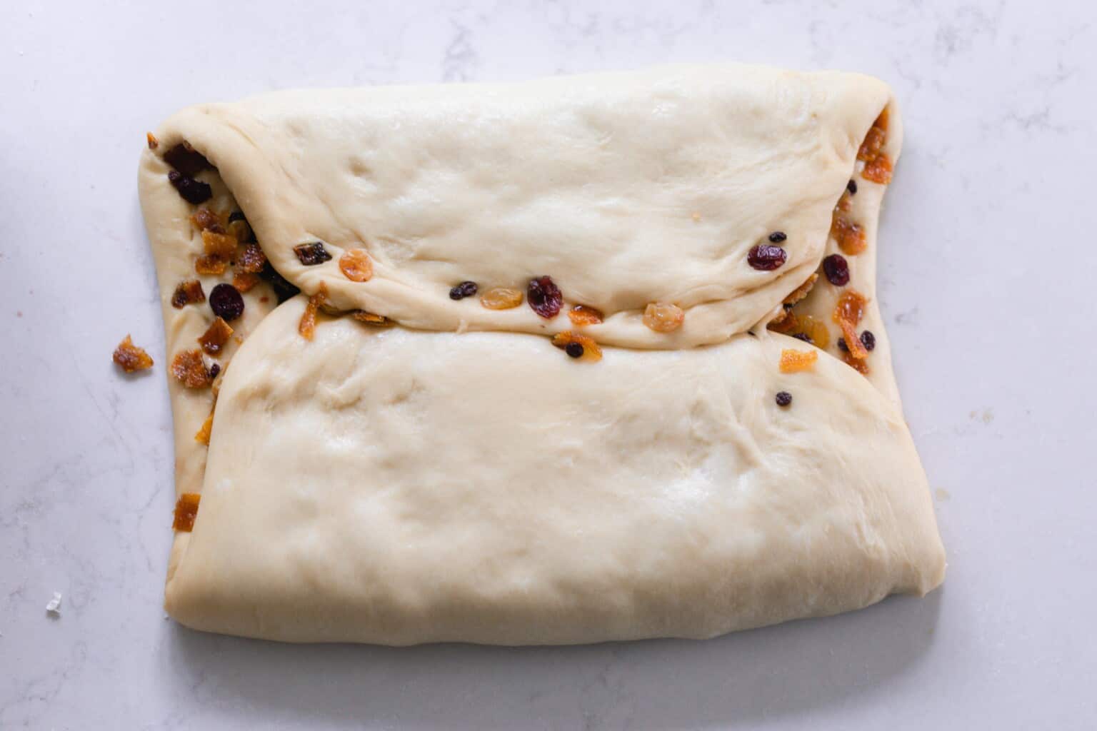 folding sourdough panettone on a white countertop