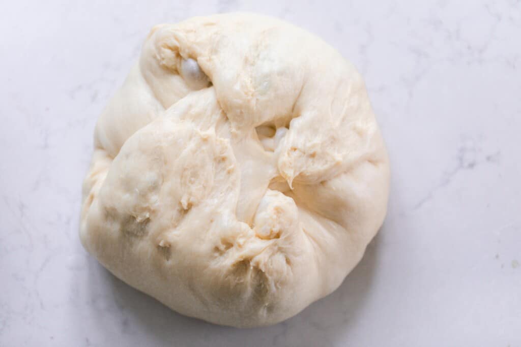 Shaping your sourdough panettone dough into a ball on a white countertop