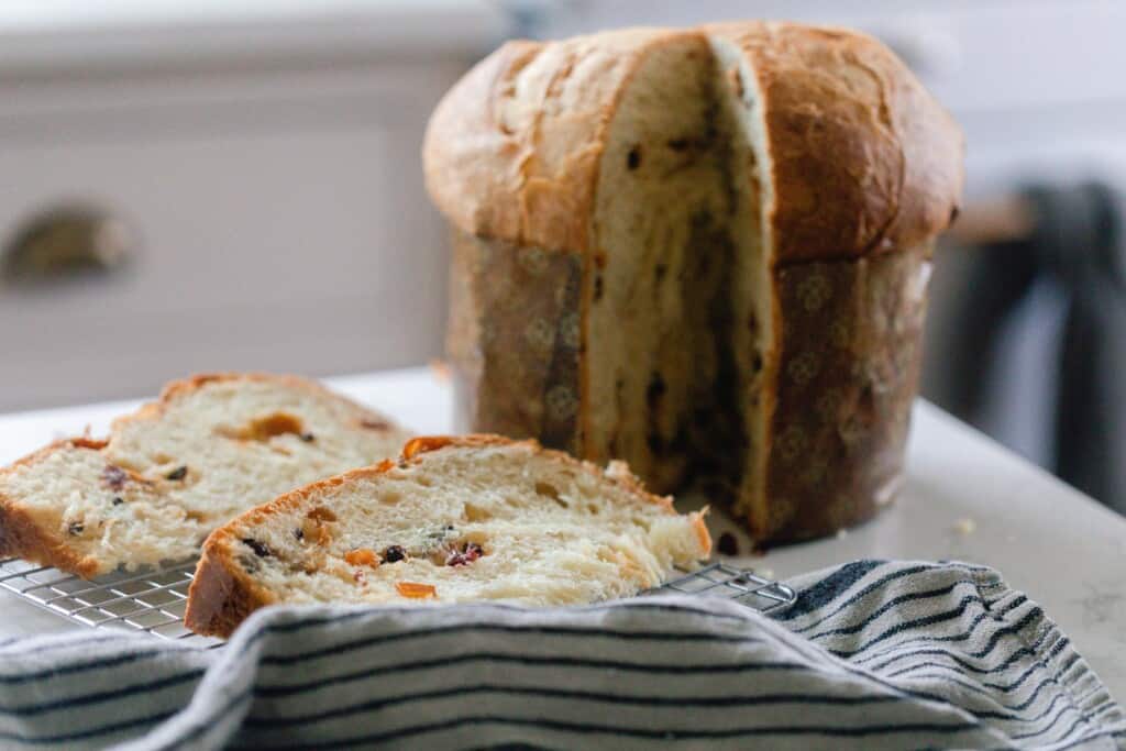two slices cut out of one loaf of sourdough panettone with a white and blue striped tea towel 