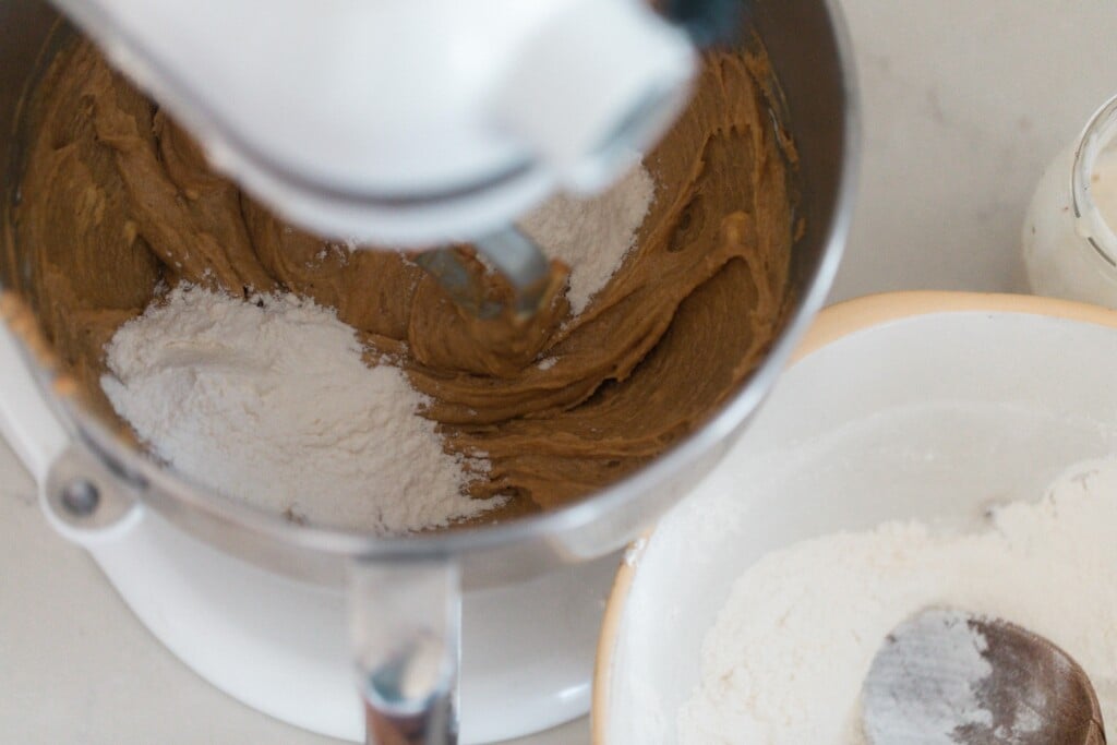 flour being added to wet ingredients in a stand mixer