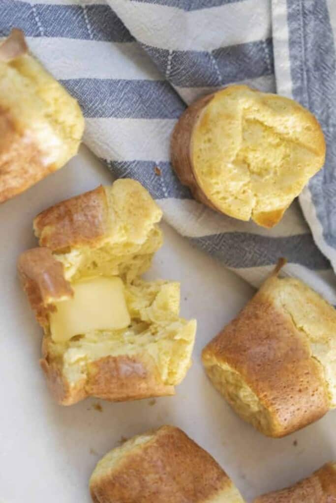 six sourdough popovers on a white countertop and blue and white stripped tea towel