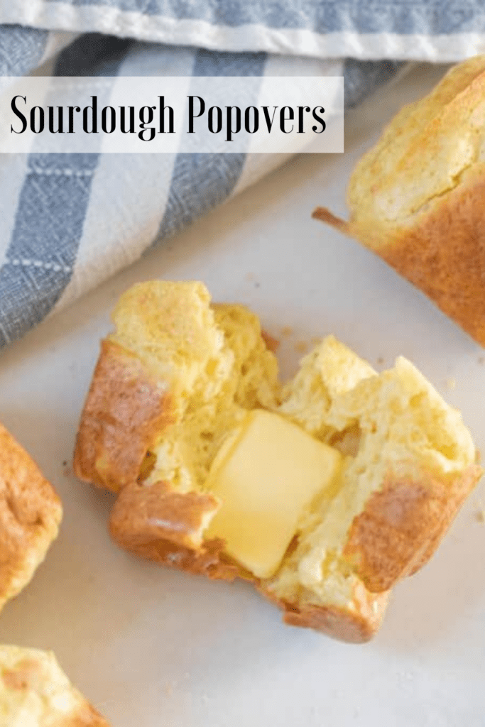 Vertical image of sourdough popovers split open with butter