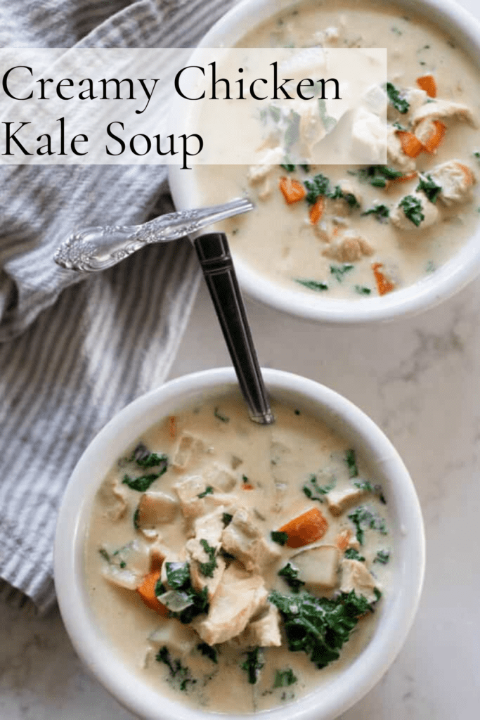 Aerial view of two bowls of chicken kale soup with silver spoons in each white bowl. white and blue striped tea towel on the side on a white marble countertop