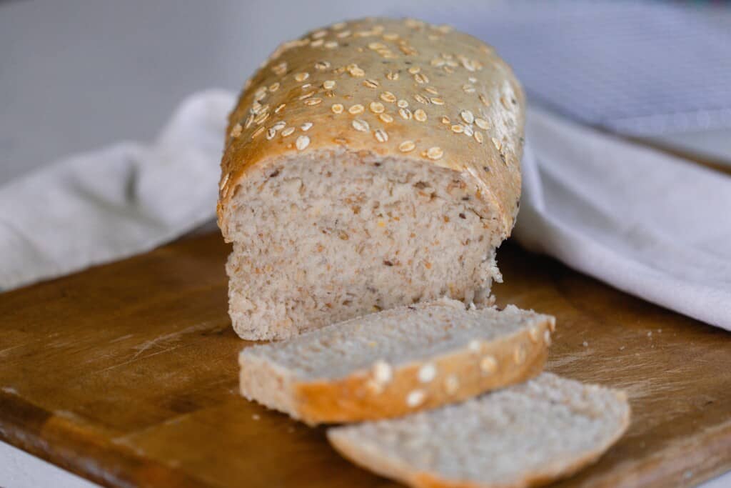 loaf of multigrain sourdough bread on a cutting board with two sliced sliced off