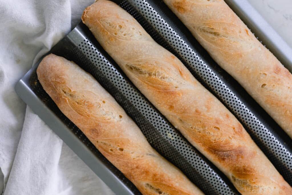 three loaves of sourdough baguettes in a baguette mold fresh out of the oven