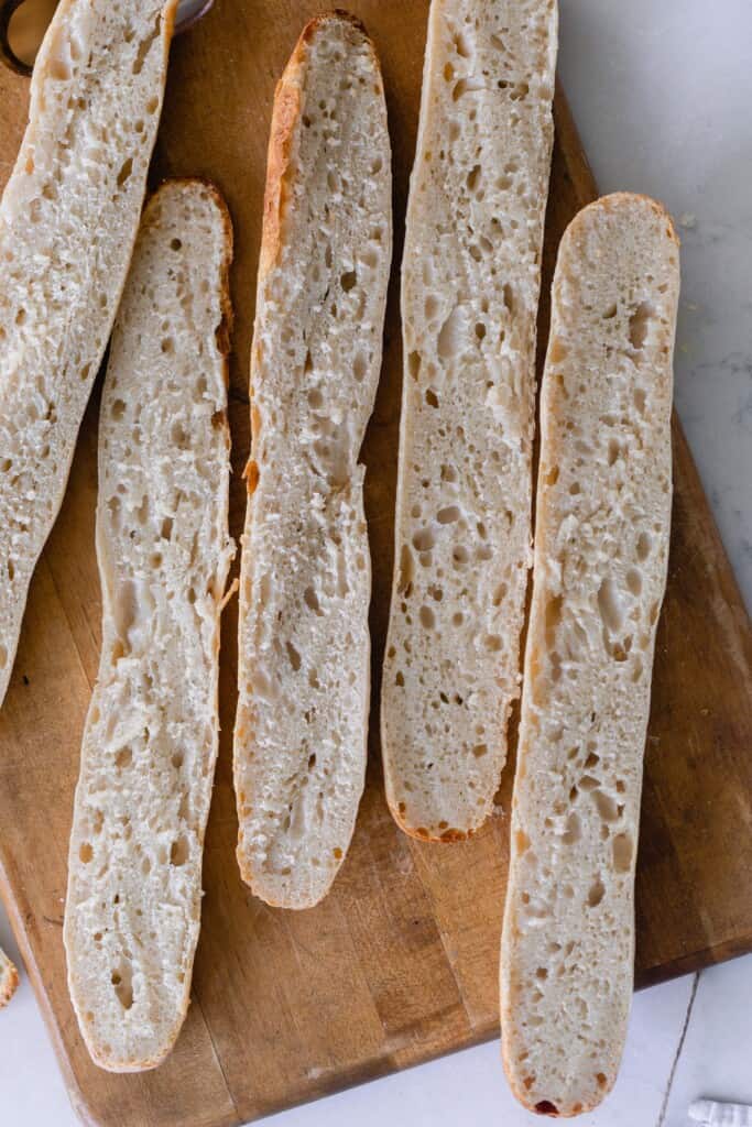 Sourdough baguettes sliced in half on a wooden cutting board