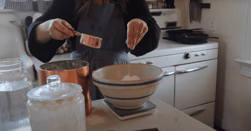 Woman measuring out flour in a large bowl on a kitchen scale