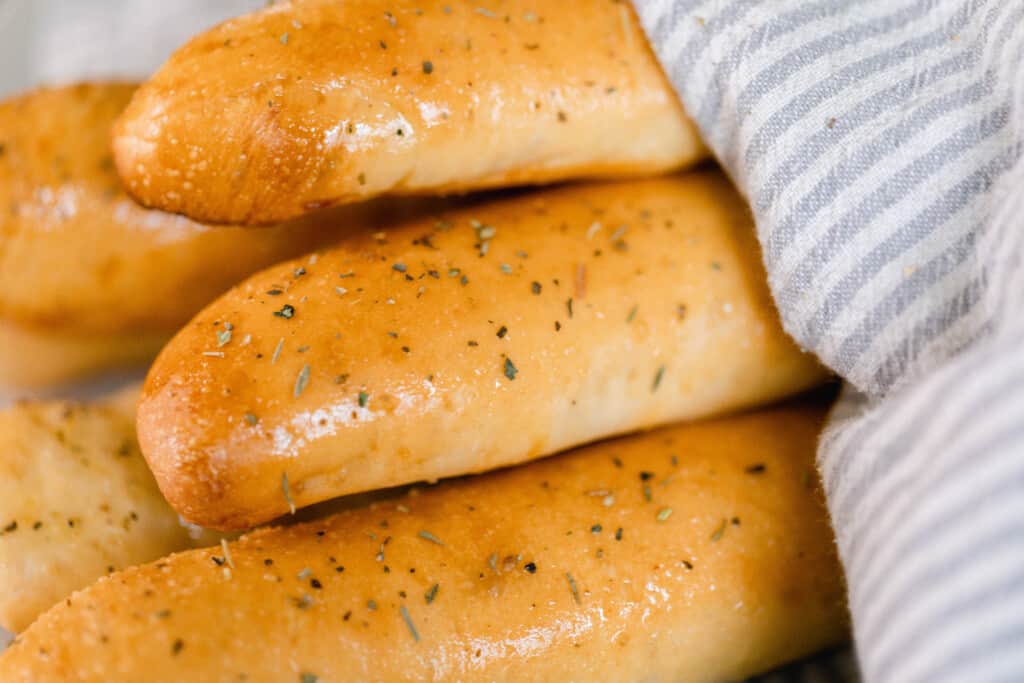close up picture of sourdough bread sticks wrapped in a gray and white towel