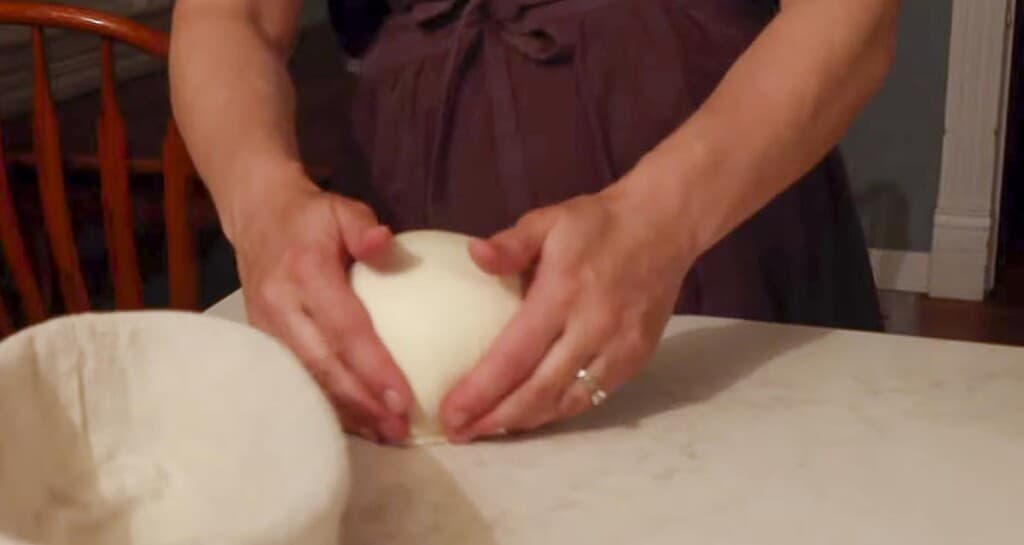 hands spinning a round loaf of bread on a white countertop