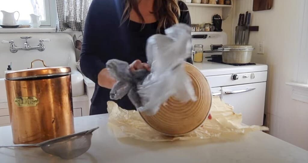 taking dough out of a banneton basket onto parchment paper