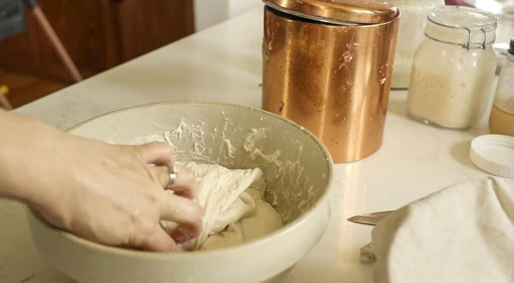 hand placing dough in the center of the bowl to complete. stretch and fold method