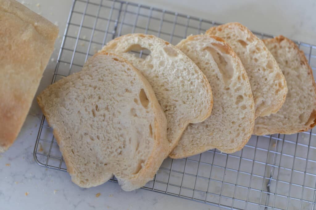 aerial view of potato flake sourdough starter sandwich bread cut into slices on a wire rack on a white counter top