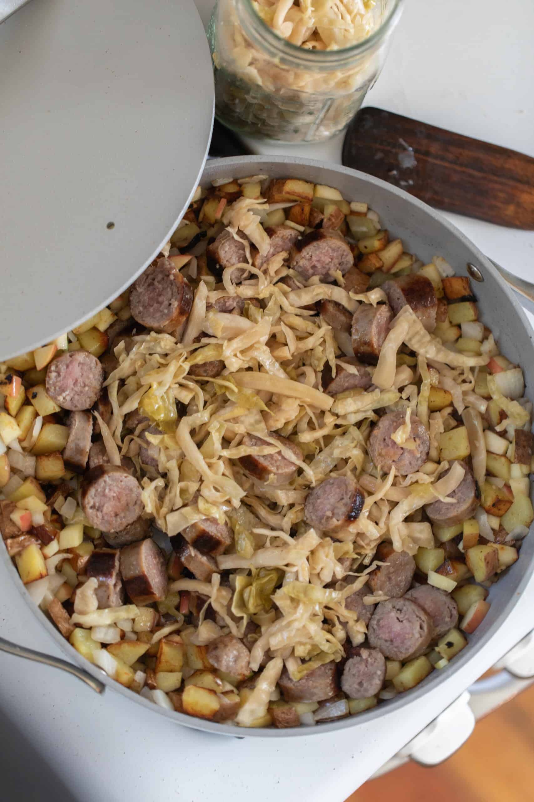 an aerial view of a large gray skillet filled with sausage and sauerkraut