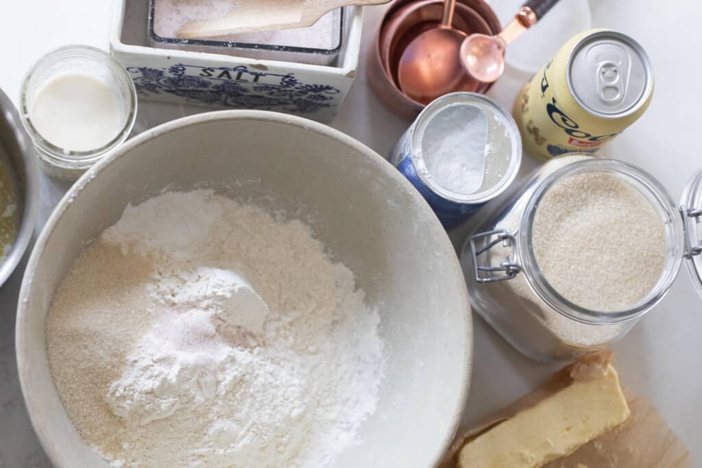 Overhead shot of cream mixing bowl with dry ingredients for sourdough beer bread with the discard and beer and butter on the side