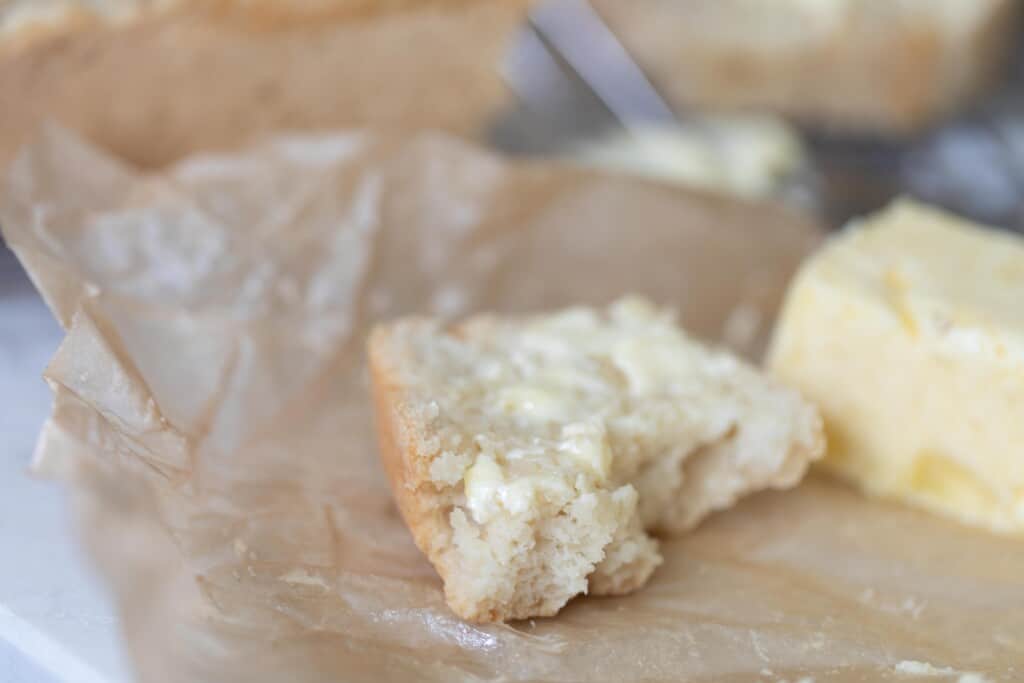 Half a slice of sourdough beer bread on parchment paper with butter on it