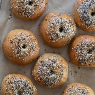 overhead photo of sourdough discard bagels topped with everything seasoning on a parchment lined baking sheet