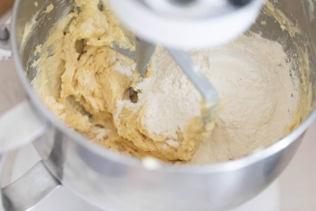 sourdough shortbread dough mixed in a stand mixer with flour being slowly added