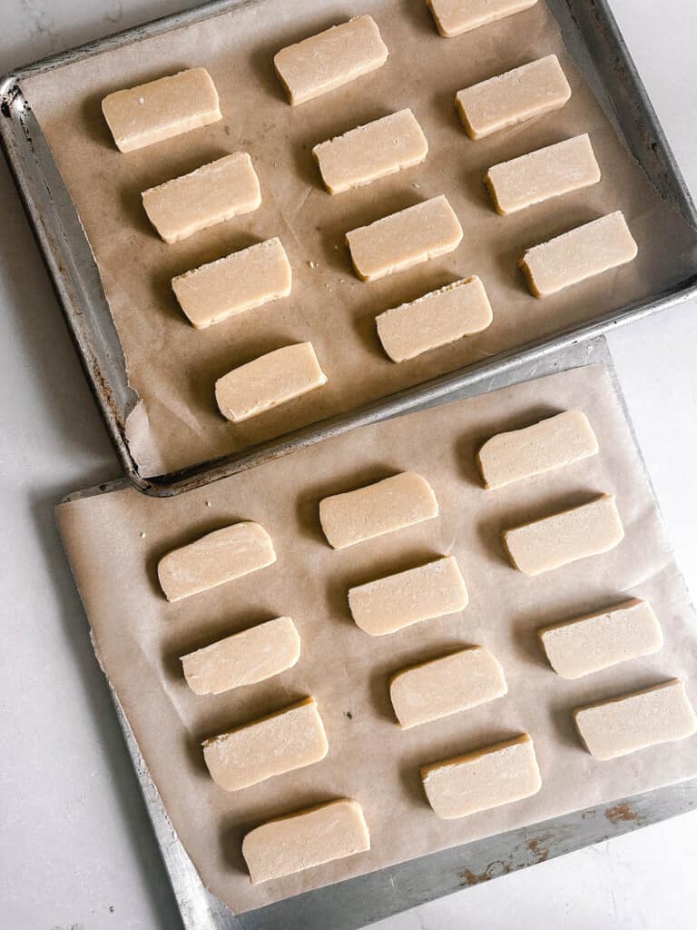 sourdough shortbread cookies on two stainless steel cookie sheets lined with parchment paper