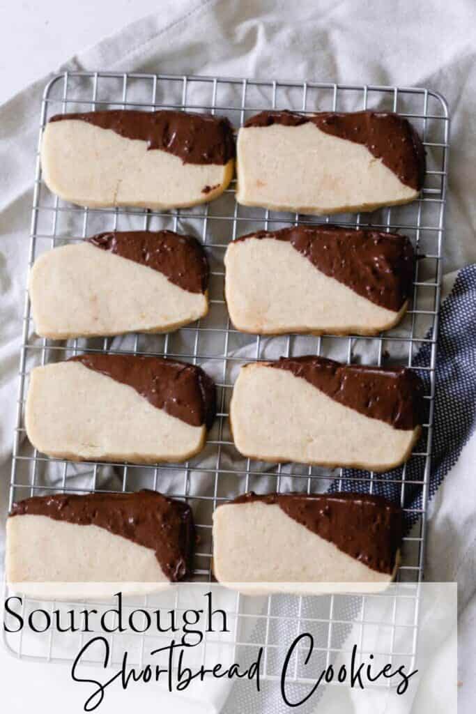 Sourdough shortbread cookies Pinterest graphic. Cookies are dipped in chocolate and cooling on a wire rack on top of a blue and white tea towel