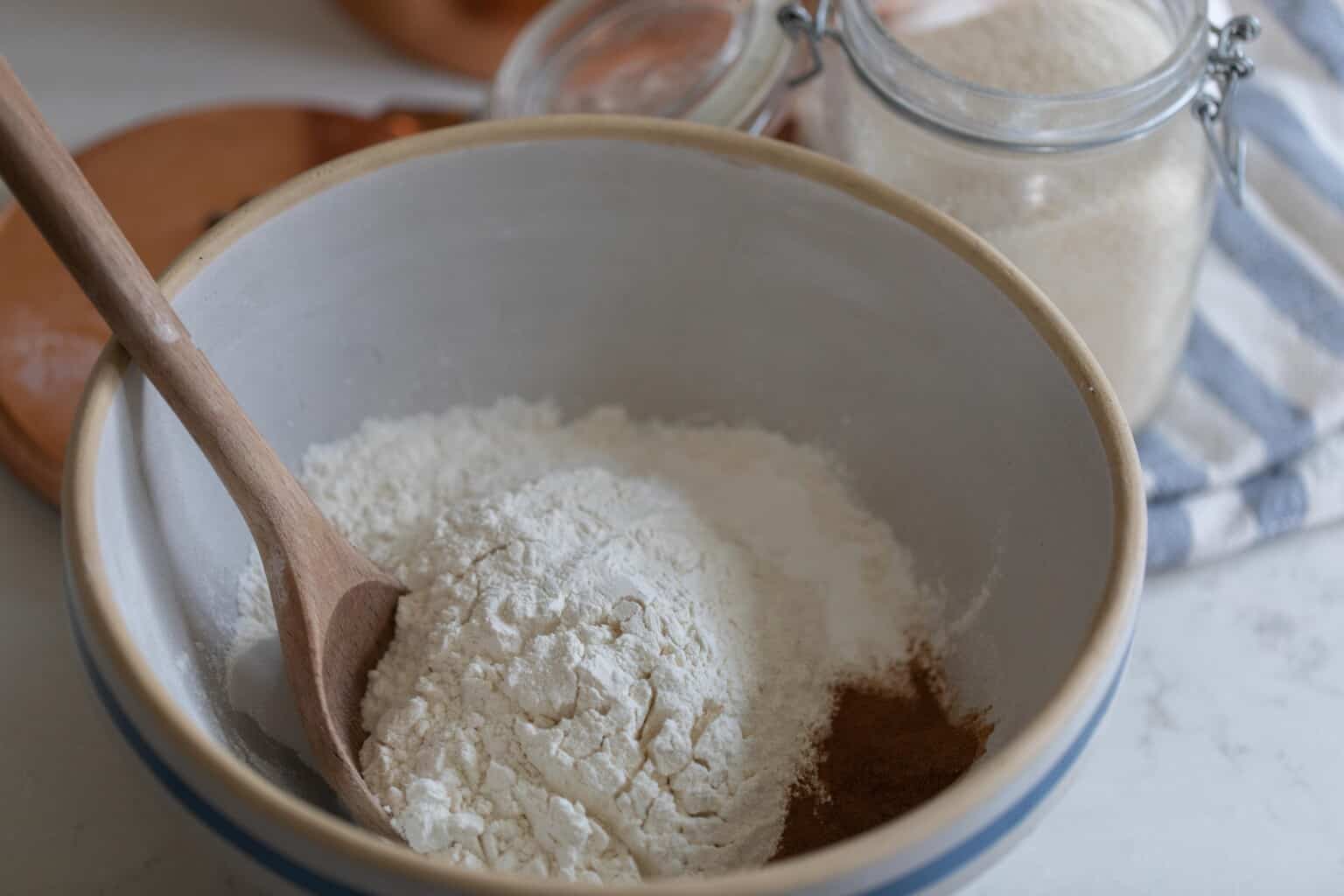dry ingredients adding to a stoneware bowl
