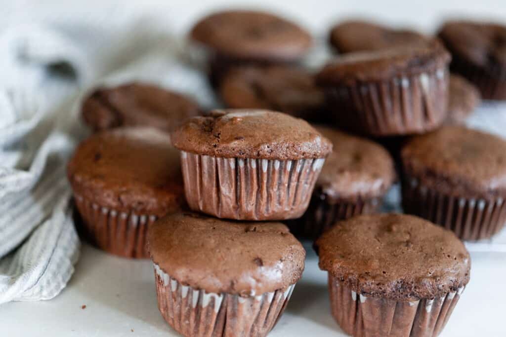 einkorn protein muffins stacked on top of each other on a white counter top with a white tea towel in background