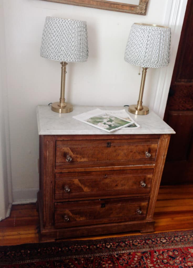 two lamps with pleaded lampshades on a antique dresser with a marble top