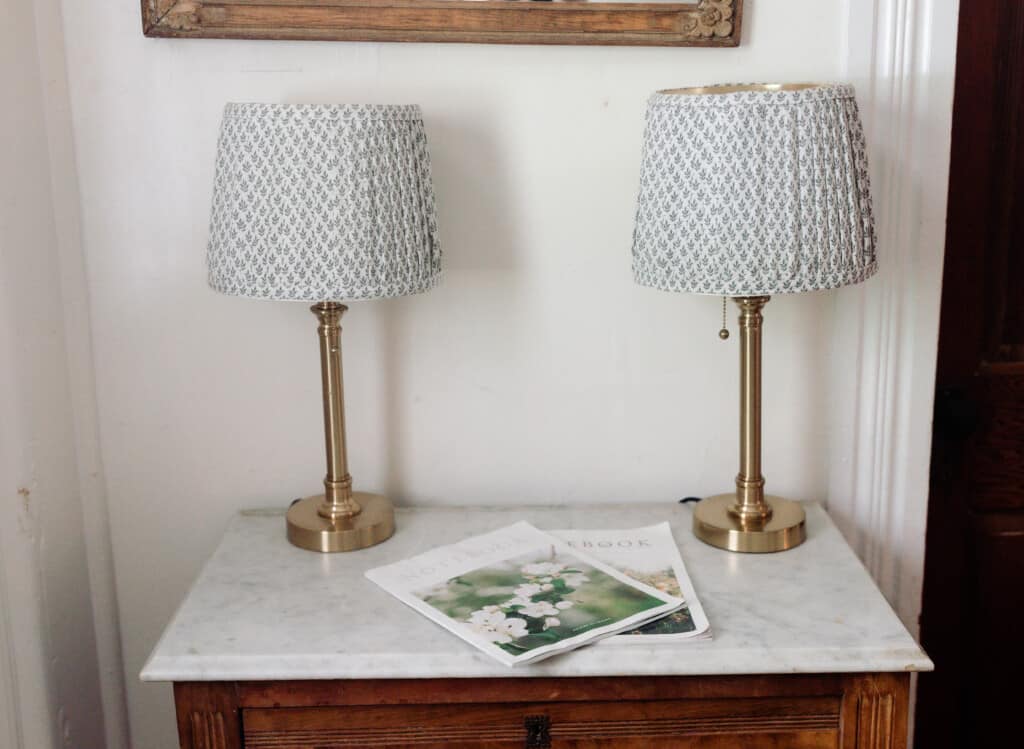 Two lamps on a white table with pleated lampshades