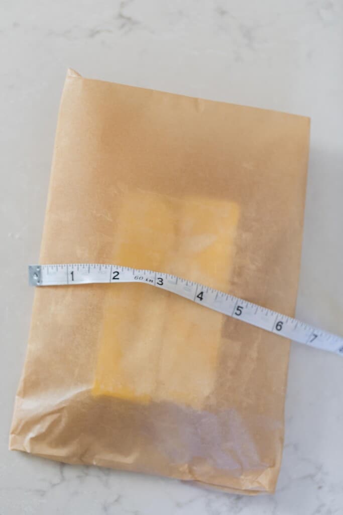 two stick of butter wrapped with parchment paper and a ruler over top 