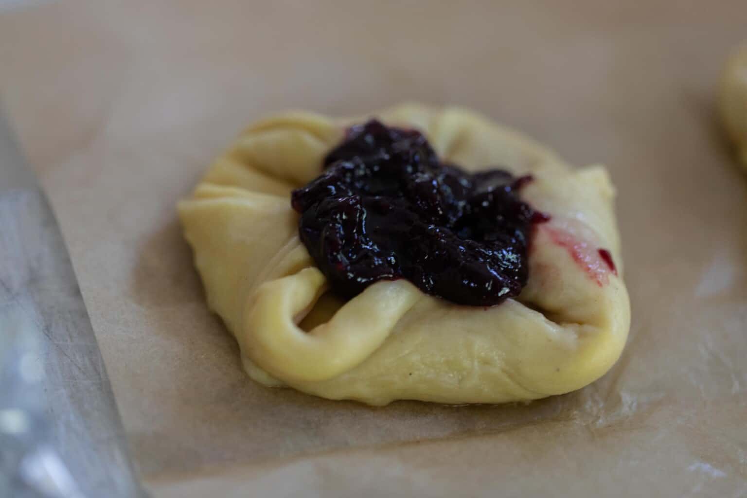 sourdough pastry dough shaped and a filling placed on top on parchment paper