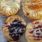 overhead photo of Danish sourdough pastries topped with cream cheese filling and jam and drizzled with a glaze on a wire rack