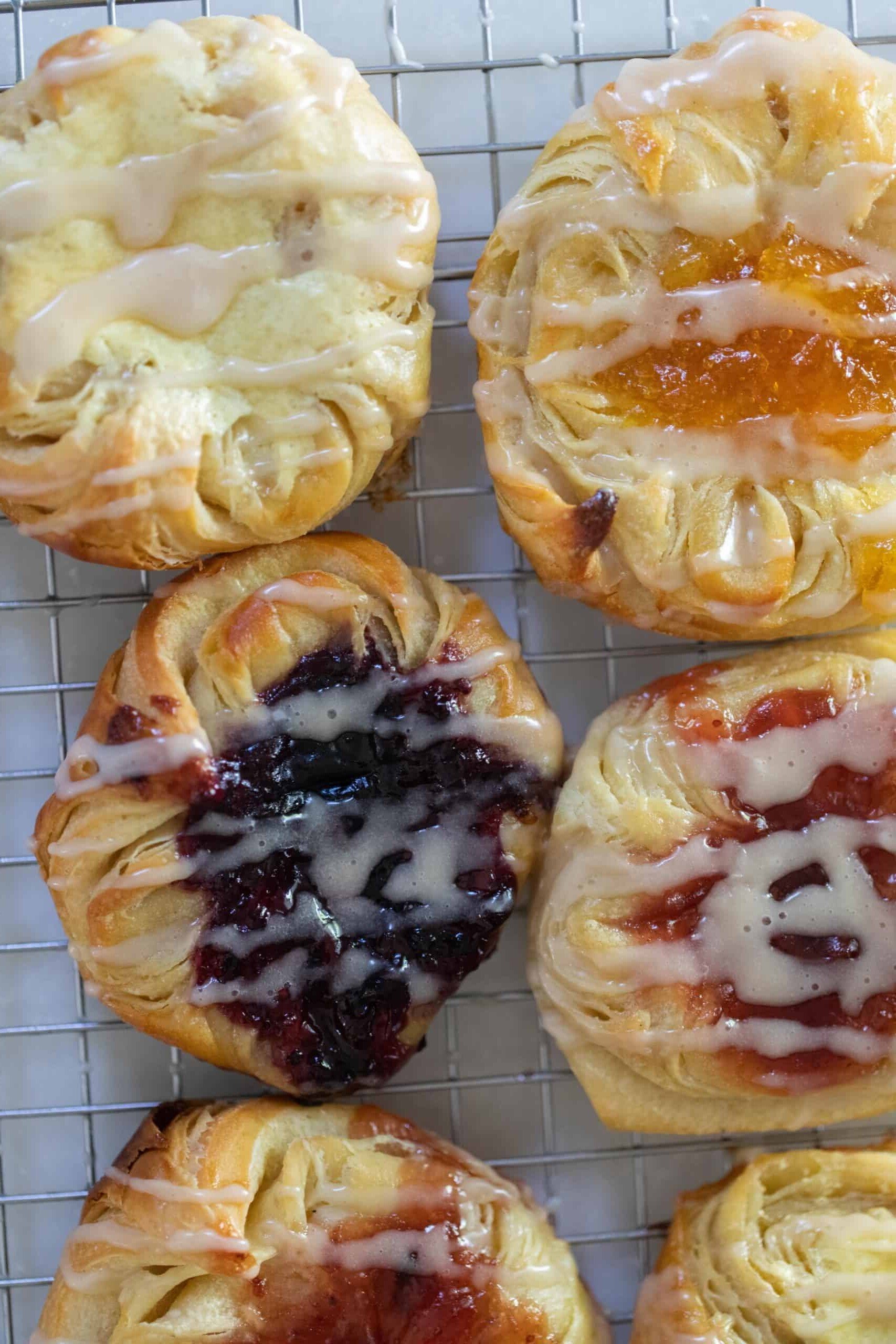 overhead photo of Danish sourdough pastries topped with cream cheese filling and jam and drizzled with a glaze on a wire rack