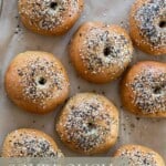 overhead photo of sourdough discard bagels topped with everything seasoning on a parchment lined baking sheet