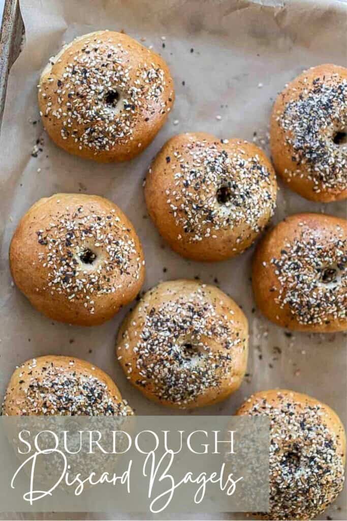 overhead photo of sourdough discard bagels topped with everything seasoning on a parchment lined baking sheet