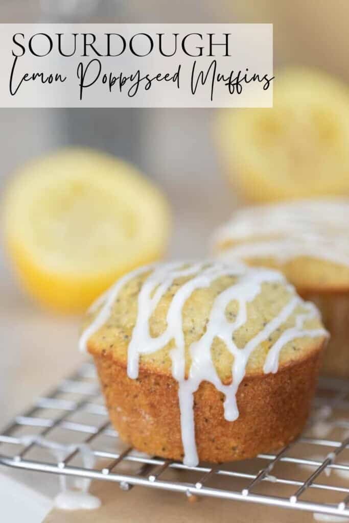 close up of a lemon poppy seed muffin with a lemon glaze on a wire rack over parchment paper with two halves of a lemon in the background