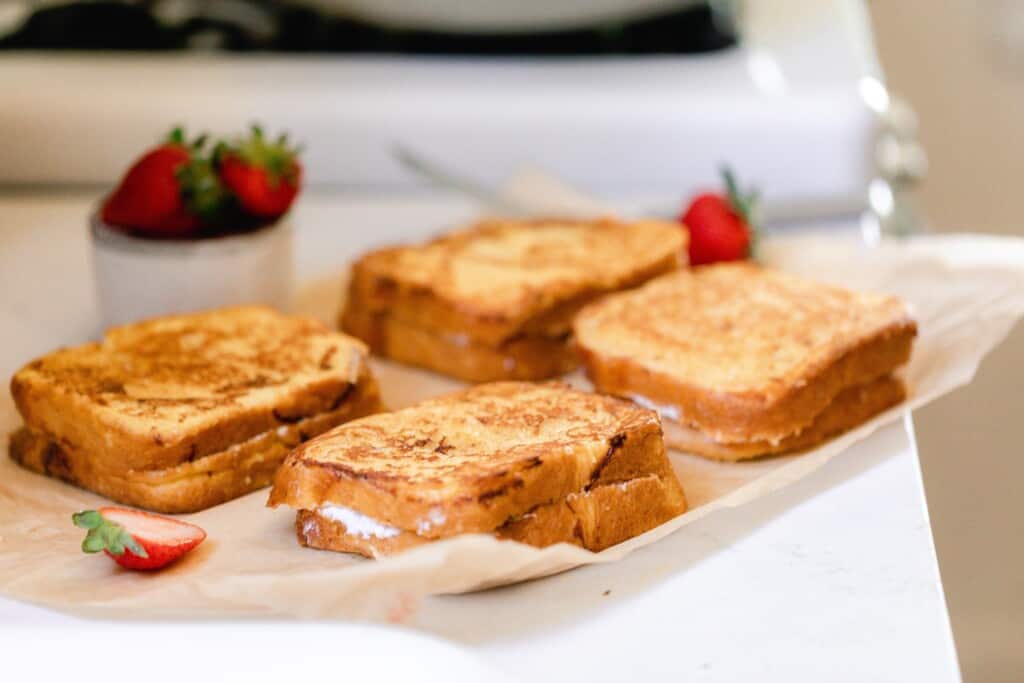 stuffed strawberry French toast fresh off the skillet on parchment paper on a countertop next to a stove