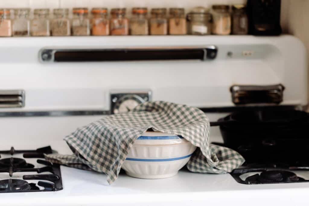 bowl with a towel covering it on a white vintage stove