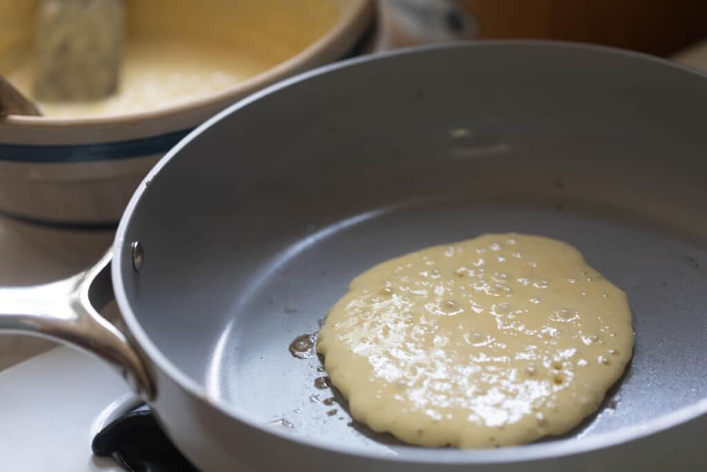 one pancake cooking on a ceramic frying pan