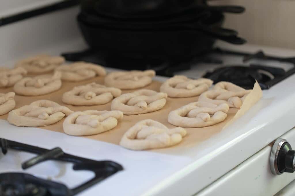 Sourdough discard pretzels rising on parchment paper on a antique stove